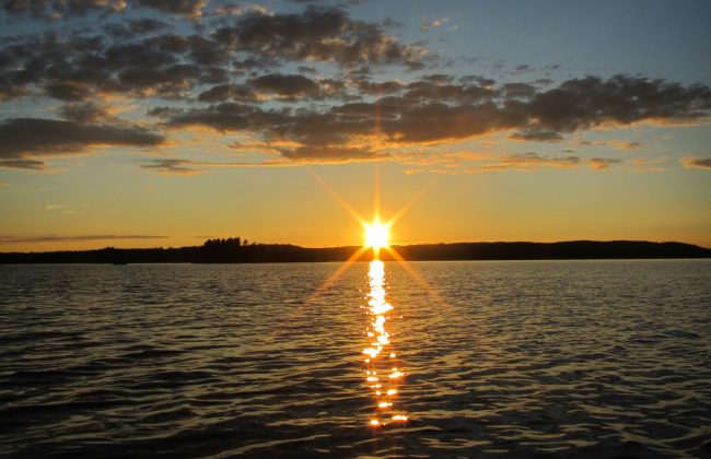 Die Sonne geht unter über einem finnischen See